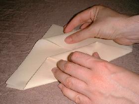 rabattre l'angle du haut (prendre une des feuilles) vers le bas et le passer sous le pli créé à l'étape précédente